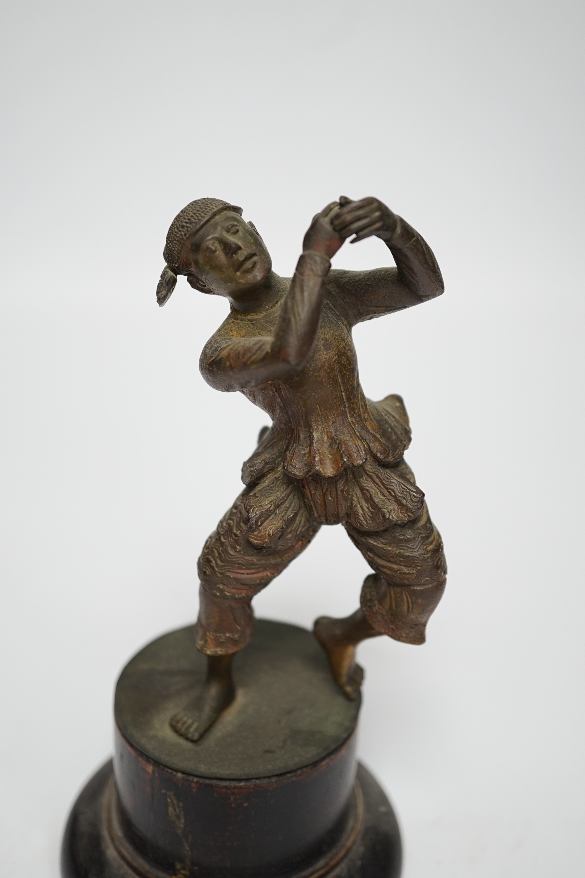 A small bronze figure of a Javanese dancer on a wooden base, 18.5cm